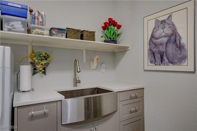 kitchen featuring gray cabinetry, a sink, open shelves, freestanding refrigerator, and light countertops