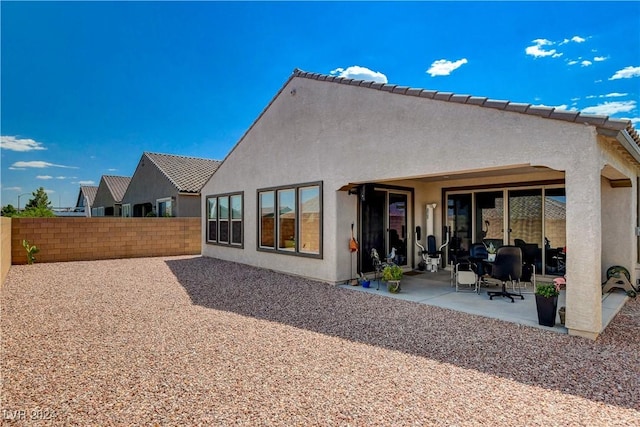 rear view of house featuring stucco siding, a patio, and fence