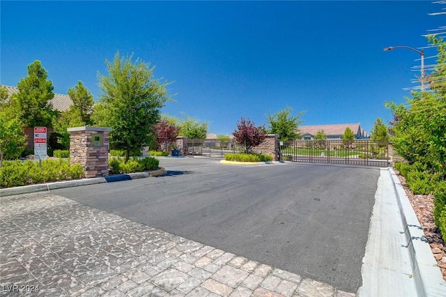 view of street featuring curbs, street lights, a gated entry, and a gate