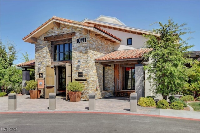 view of front of property featuring a tiled roof and stone siding