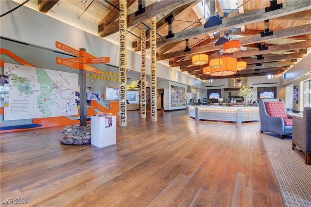 living area with beamed ceiling, high vaulted ceiling, wood ceiling, and hardwood / wood-style flooring