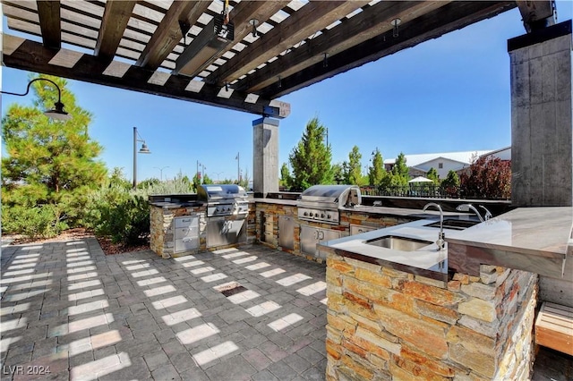 view of patio featuring grilling area, an outdoor kitchen, a pergola, and a sink