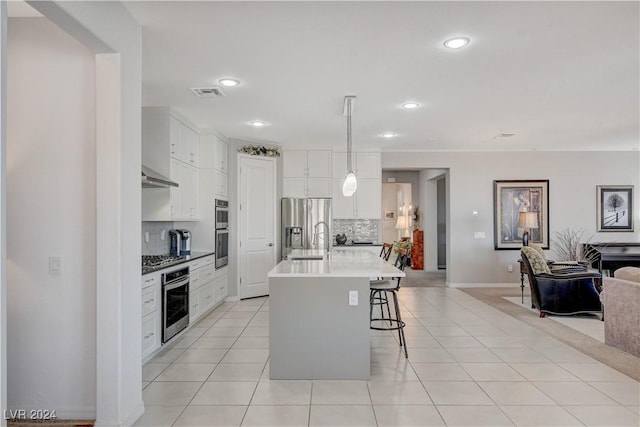 kitchen with pendant lighting, a center island with sink, and white cabinets