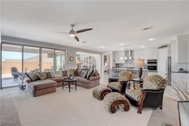 living area with visible vents, light colored carpet, and ceiling fan