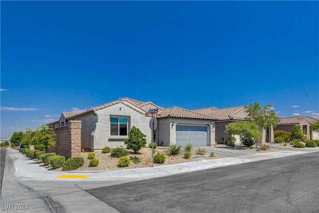 mediterranean / spanish house with a tile roof, a garage, driveway, and stucco siding