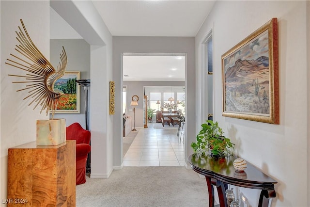 hallway with baseboards, carpet, and tile patterned flooring