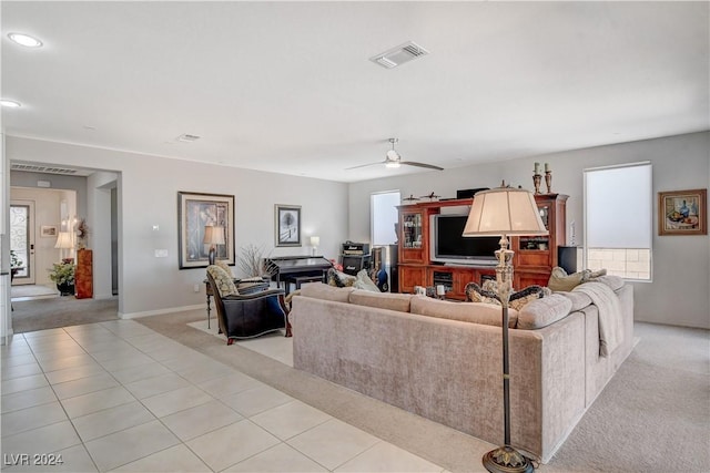 living room featuring light tile patterned floors, a ceiling fan, baseboards, visible vents, and light carpet