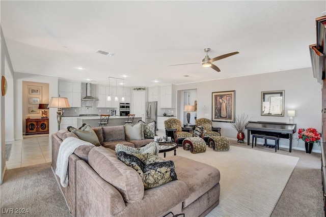 living area with visible vents, light carpet, washing machine and dryer, light tile patterned floors, and ceiling fan