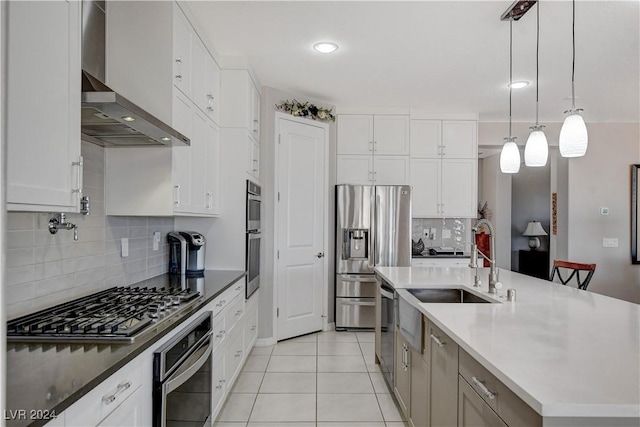 kitchen featuring light tile patterned floors, a kitchen island with sink, stainless steel appliances, hanging light fixtures, and white cabinets