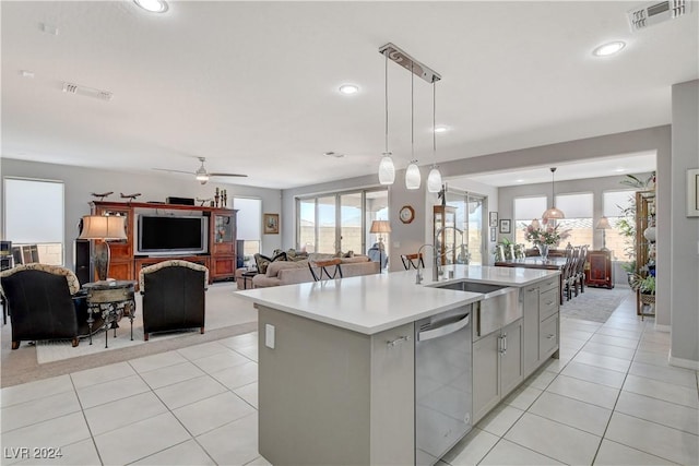 kitchen featuring dishwasher, light countertops, an island with sink, and visible vents