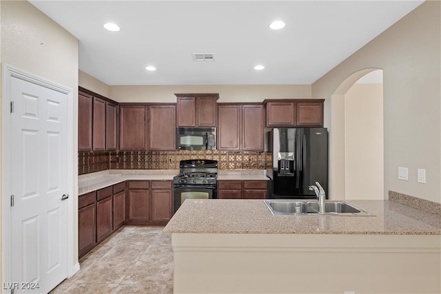 kitchen featuring sink, tasteful backsplash, light stone counters, kitchen peninsula, and black appliances