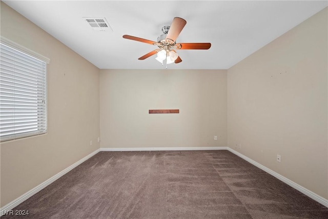 empty room featuring ceiling fan and dark carpet