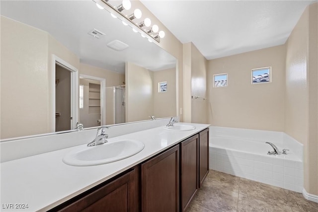 bathroom featuring vanity, a relaxing tiled tub, tile patterned floors, and a wealth of natural light