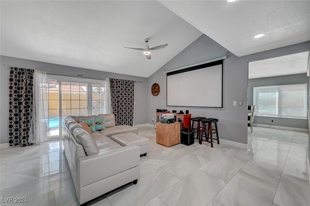 home theater featuring a wealth of natural light, ceiling fan, vaulted ceiling, and a textured ceiling