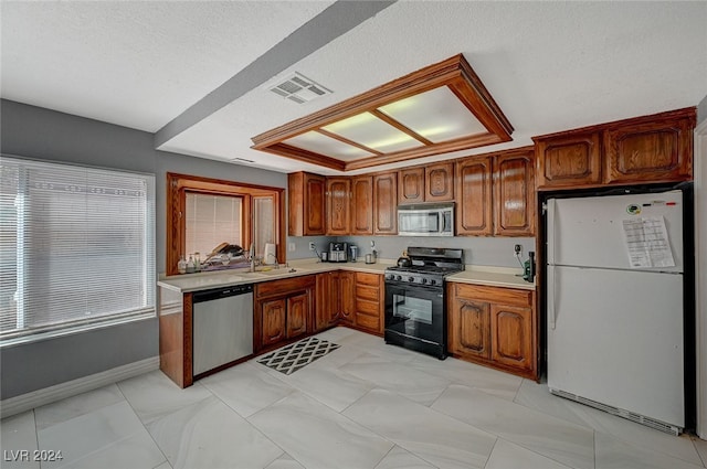 kitchen with appliances with stainless steel finishes, a textured ceiling, and sink