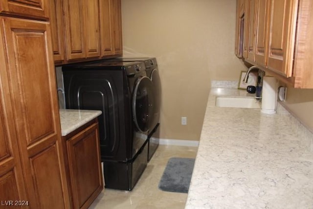 clothes washing area featuring cabinets, sink, and washing machine and clothes dryer