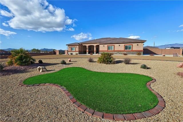 back of house with a mountain view and a lawn