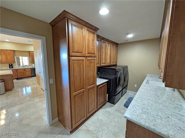 clothes washing area featuring cabinets, washing machine and dryer, and sink