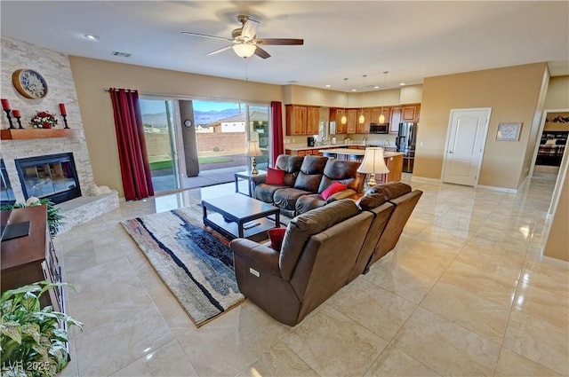 living room with a stone fireplace and ceiling fan