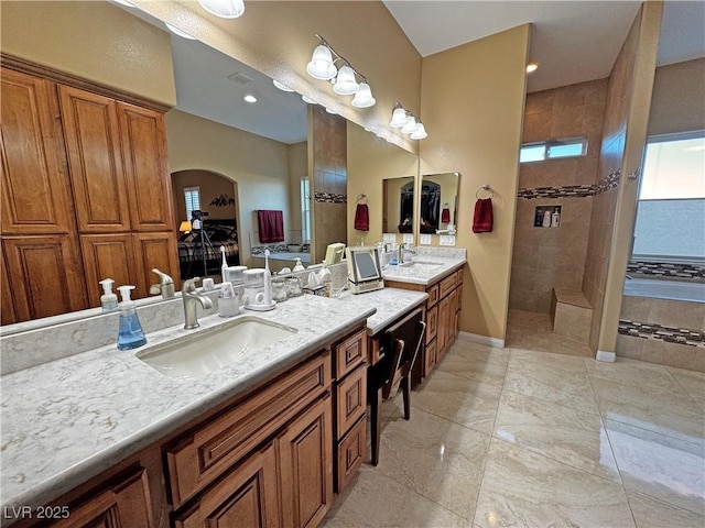 bathroom with a wealth of natural light, a tile shower, and vanity