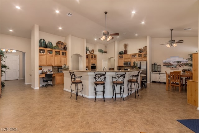 kitchen featuring a large island, light stone countertops, stainless steel appliances, a kitchen breakfast bar, and high vaulted ceiling