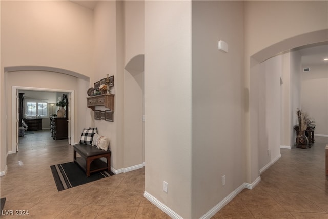 hallway featuring a high ceiling and light tile patterned floors