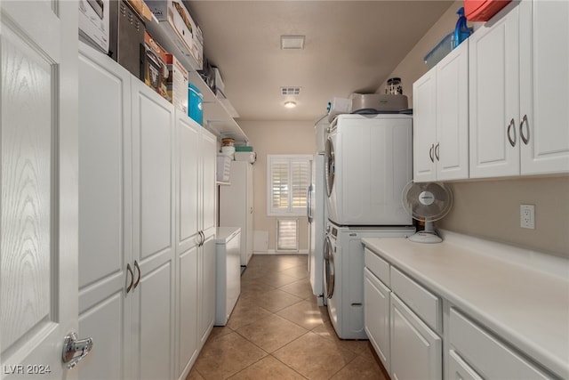 kitchen with light tile patterned flooring, white cabinetry, and stacked washer / dryer