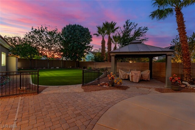 patio terrace at dusk featuring a gazebo and a lawn