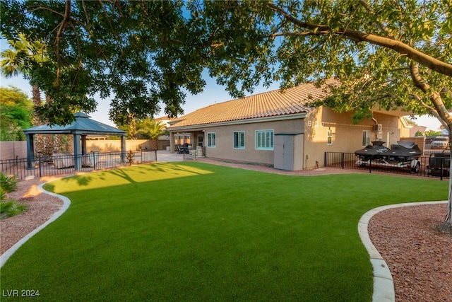 rear view of house with a gazebo, a yard, and a patio