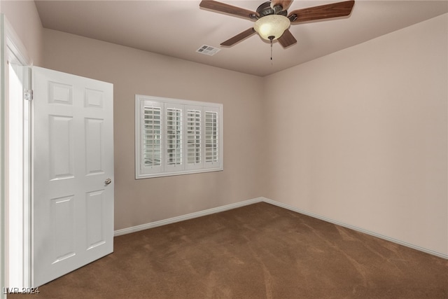 spare room featuring ceiling fan and dark carpet