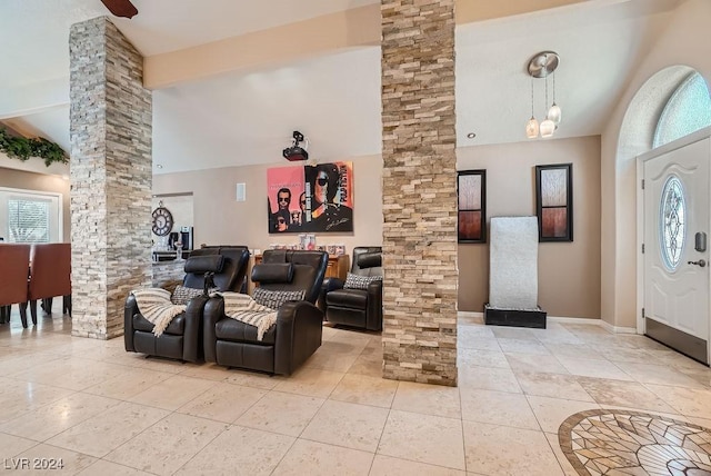 interior space with baseboards, ornate columns, and high vaulted ceiling