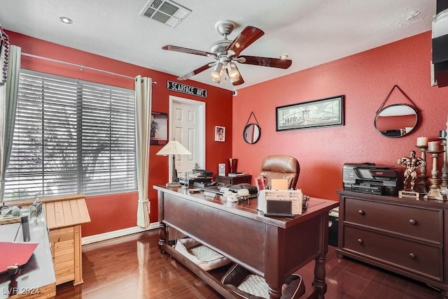 office space with visible vents, baseboards, wood finished floors, a textured wall, and a ceiling fan