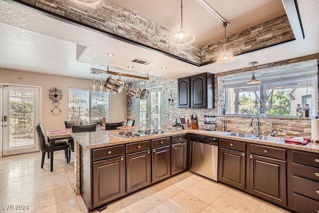 kitchen with dark brown cabinets, a tray ceiling, appliances with stainless steel finishes, a peninsula, and a sink