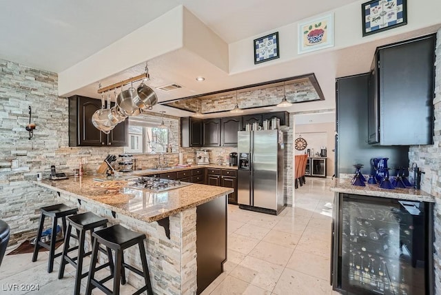 kitchen featuring beverage cooler, visible vents, a peninsula, a sink, and stainless steel appliances