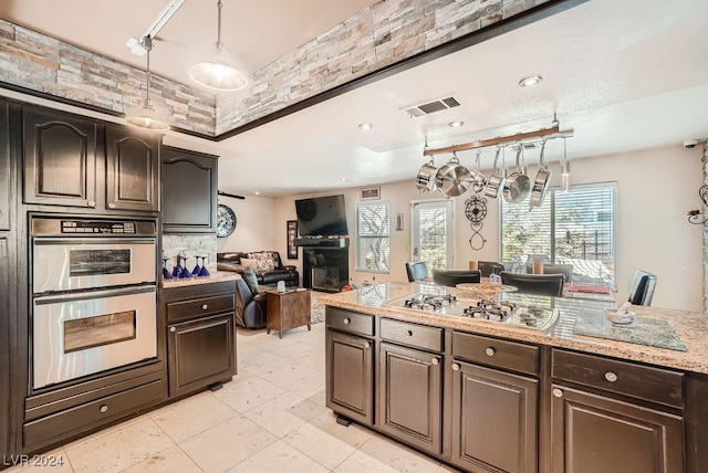 kitchen featuring light tile patterned floors, dark brown cabinets, decorative light fixtures, and stainless steel appliances