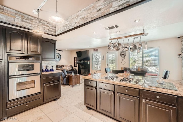 kitchen with dark brown cabinetry, decorative light fixtures, visible vents, and appliances with stainless steel finishes