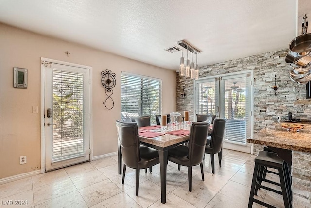 dining space featuring light tile patterned floors, baseboards, and a textured ceiling