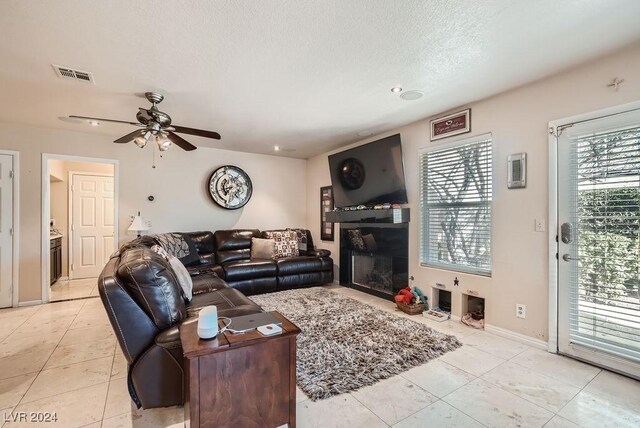 living room featuring ceiling fan, light tile patterned floors, and a textured ceiling