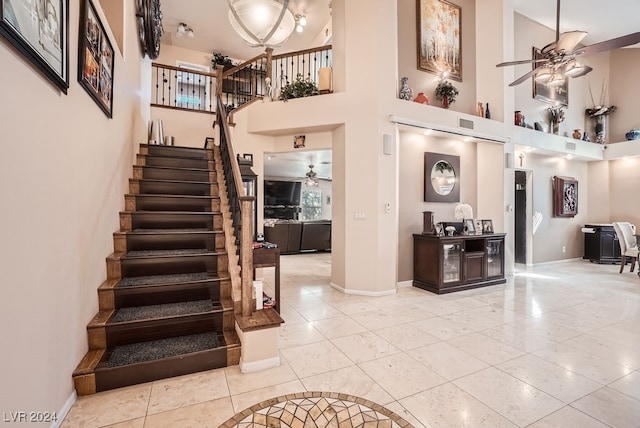 interior space featuring a high ceiling, ceiling fan, and light tile patterned floors