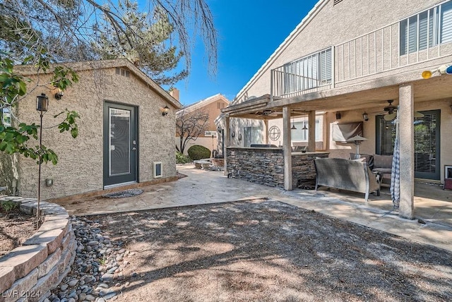 view of patio featuring area for grilling, an outdoor structure, and a ceiling fan