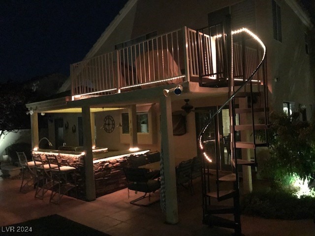 back house at night featuring a patio area and a balcony