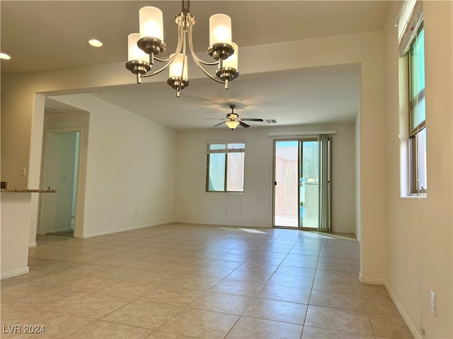 spare room featuring light tile patterned floors and ceiling fan with notable chandelier