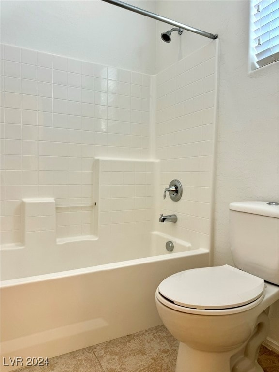 bathroom featuring tiled shower / bath combo, toilet, and tile patterned flooring