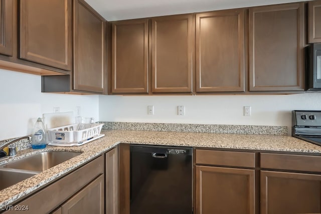 kitchen with black appliances, light stone counters, and sink