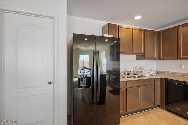 kitchen featuring light stone counters, refrigerator with ice dispenser, sink, and light tile patterned floors