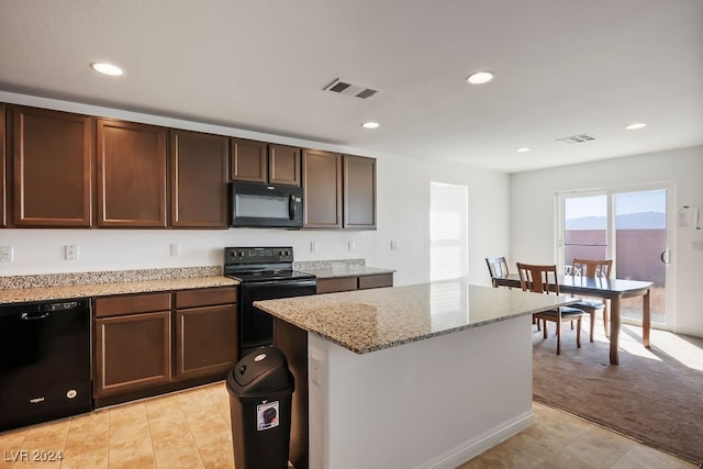 kitchen featuring light stone countertops, dark brown cabinets, black appliances, a center island, and light colored carpet