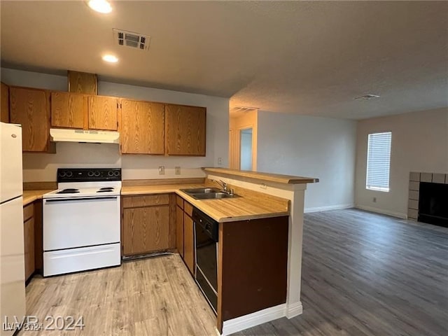 kitchen with kitchen peninsula, light wood-type flooring, a fireplace, sink, and white appliances