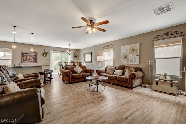 living room featuring light hardwood / wood-style flooring and ceiling fan with notable chandelier