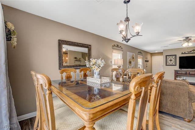 dining area with ceiling fan with notable chandelier and light wood-type flooring