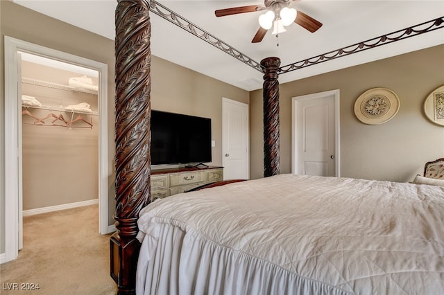 bedroom with light carpet, a spacious closet, ceiling fan, and a closet